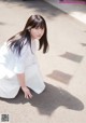 A woman in a white dress crouching down on the ground.