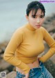 A woman in a yellow sweater and jeans posing for a magazine.