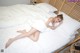 A woman laying on a bed with white sheets and pillows.