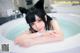 A woman in a bathtub with a cat ears headband.