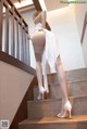 A woman in white stockings and high heels is standing on the stairs.