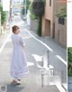 A woman in a long dress is walking down the street.