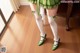 A woman in a green dress and white stockings standing on a wooden floor.