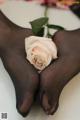 A pair of black stockings with a pink rose on top of them.