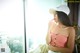 A woman in a pink top and white hat smoking a cigarette.