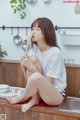 A woman sitting on a kitchen counter holding a wooden spoon.